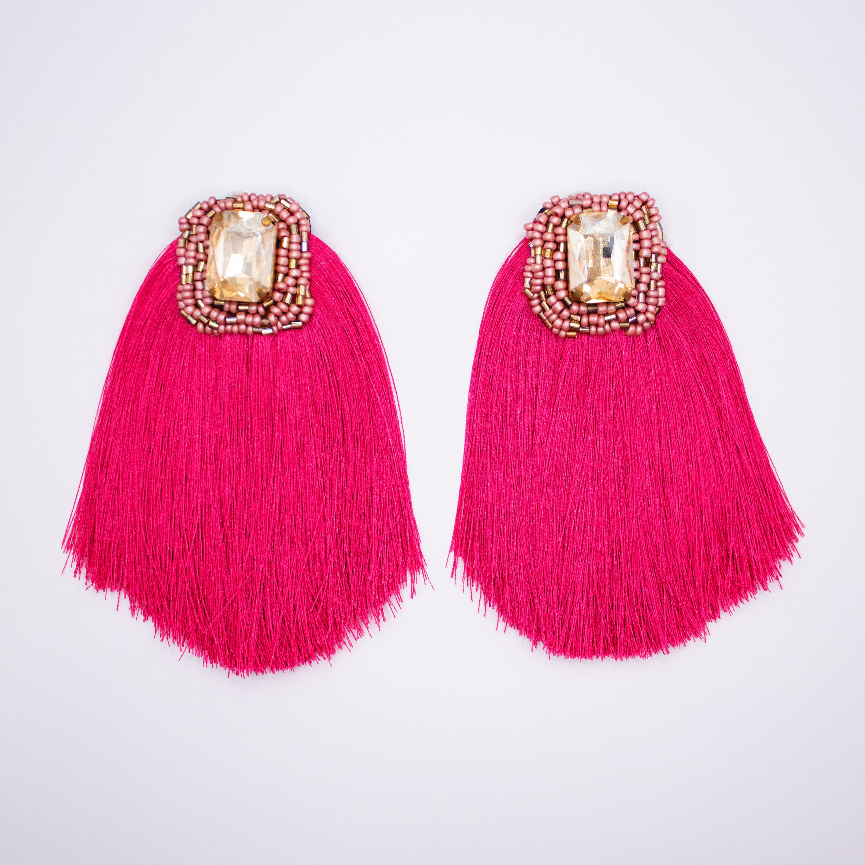 Pair of pink tassel earrings with decorative elements on a light gray background