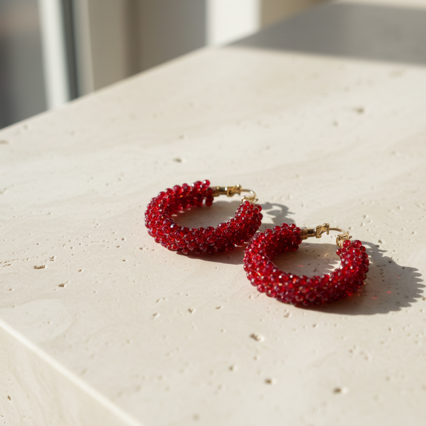 Red beaded hoop earrings on a light surface