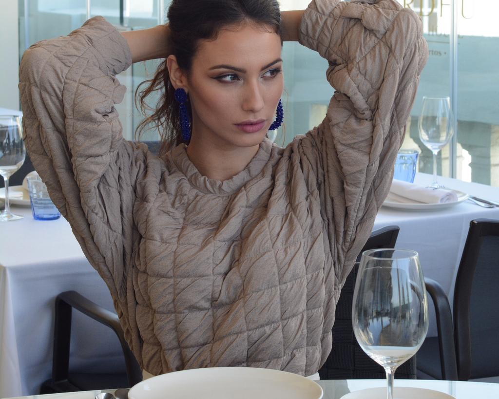 Woman sitting at a table with a plate and wine glass in a restaurant setting
