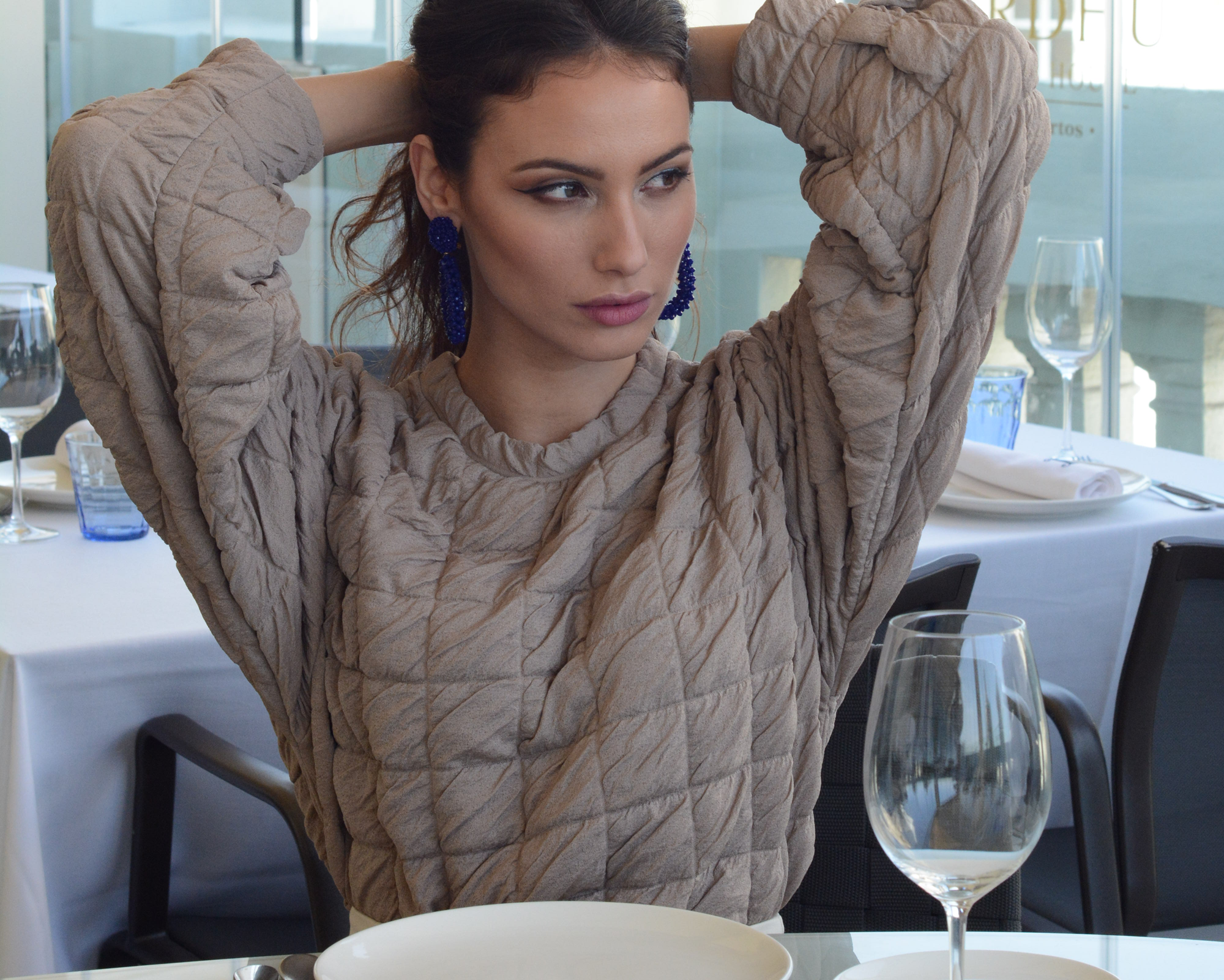 Woman sitting at a table with a plate and wine glass in a restaurant setting
