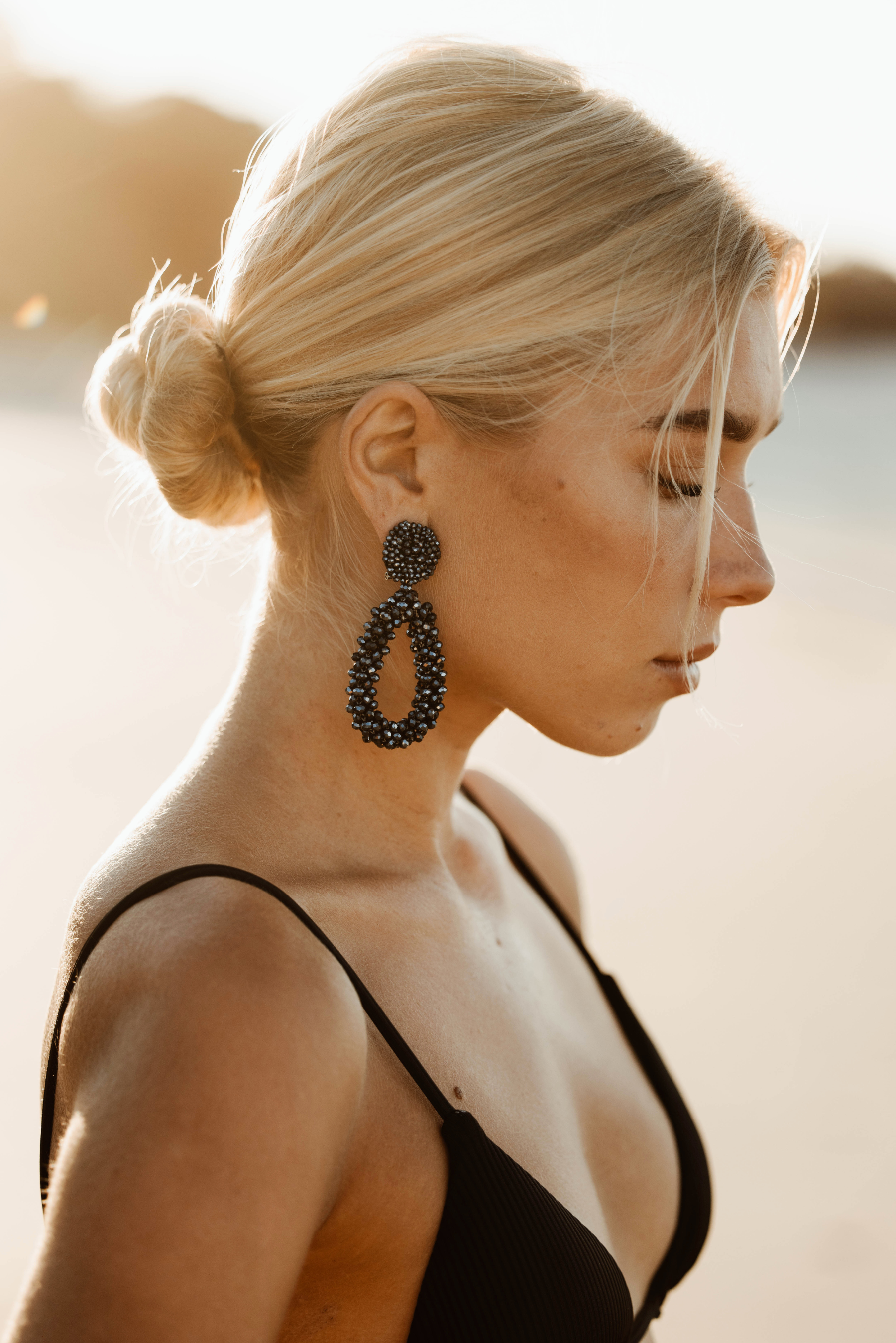 Woman wearing large black beaded earrings with a blurred background