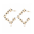 Gold hoop earrings with black and white bead accents on a white background