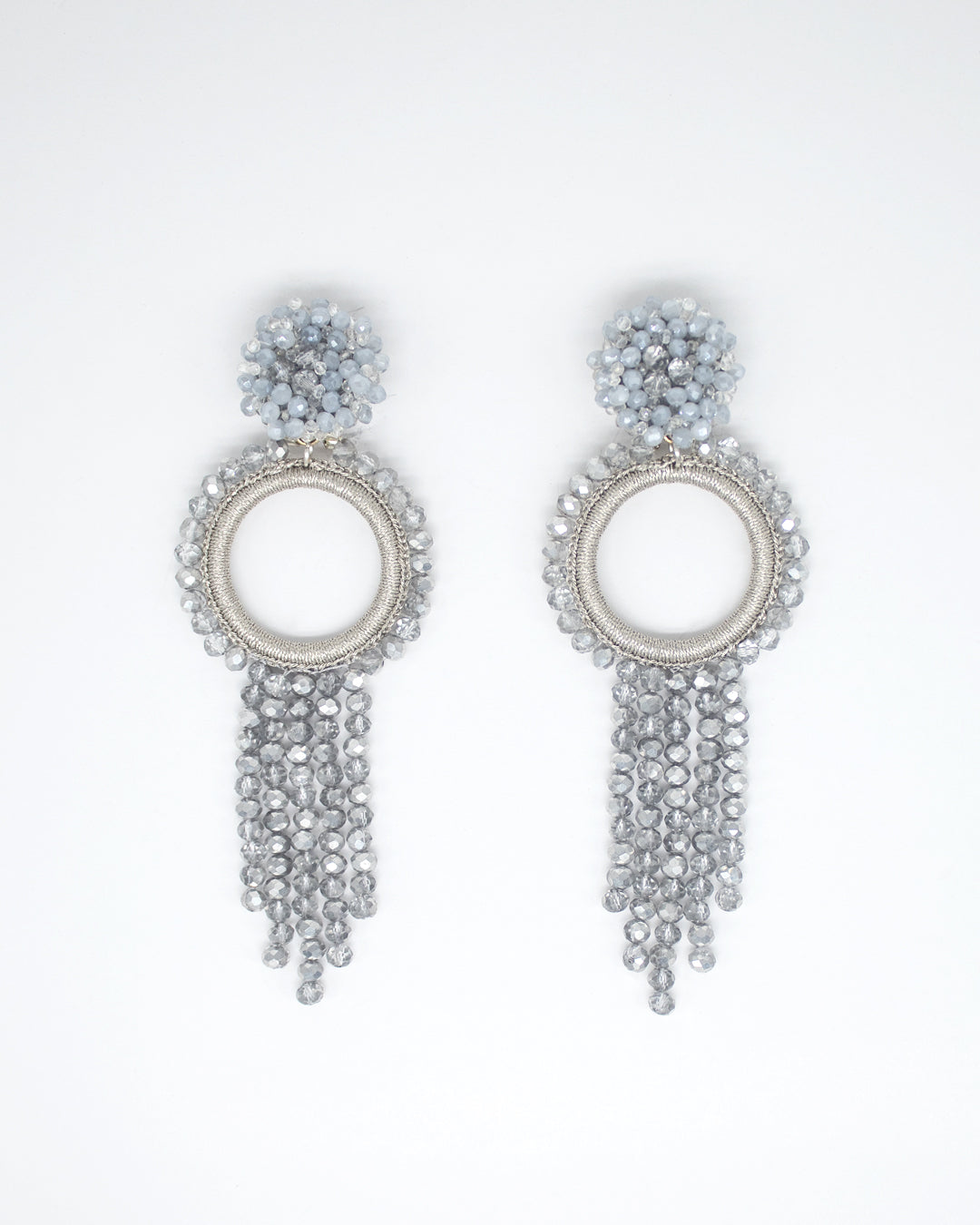 Pair of silver earrings with circular design and dangling beads on a white background